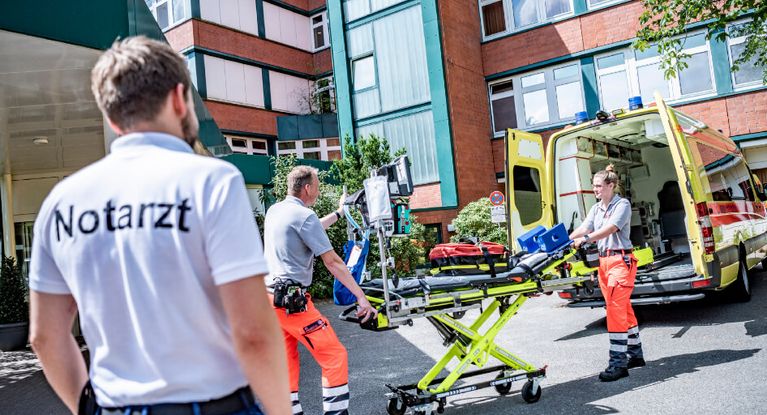 Sanitäter heben eine Krankenbahre aus dem Rettungswagen