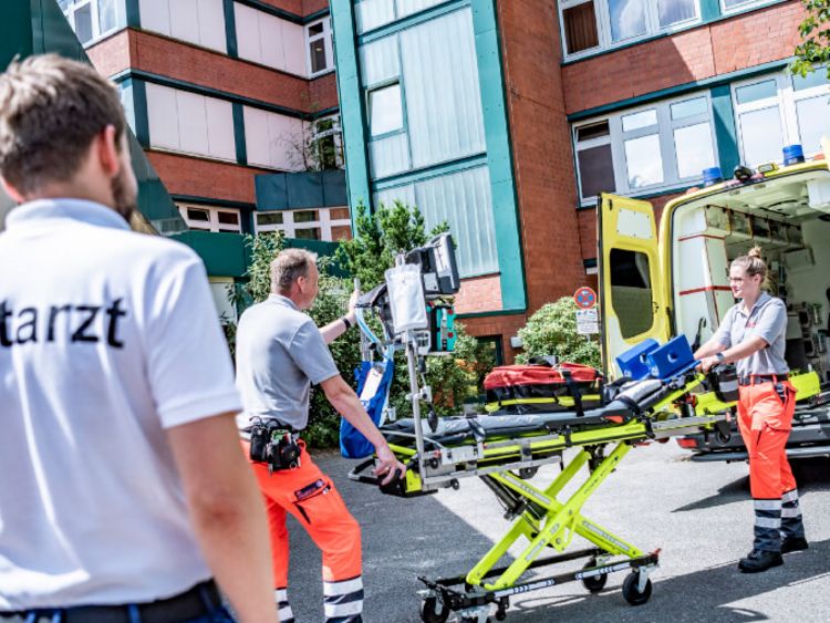 Sanitäter heben eine Krankenbahre aus dem Rettungswagen