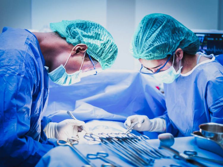 Eine Ärztin und ein Arzt mit Mundschutz sortieren chirurgische Instrumente vor einer Operation