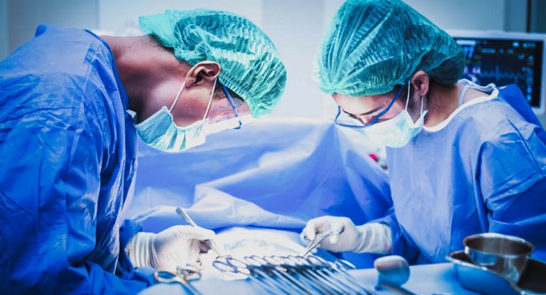 Eine Ärztin und ein Arzt mit Mundschutz sortieren chirurgische Instrumente vor einer Operation