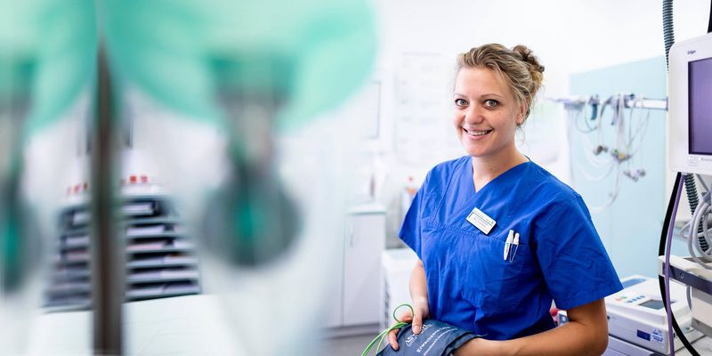 Pflegekraft hält Messgerät im Patientenzimmer