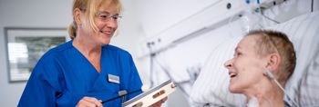 Pflegekraft und neurologische Patientin spielen auf kleinen Handtrommeln