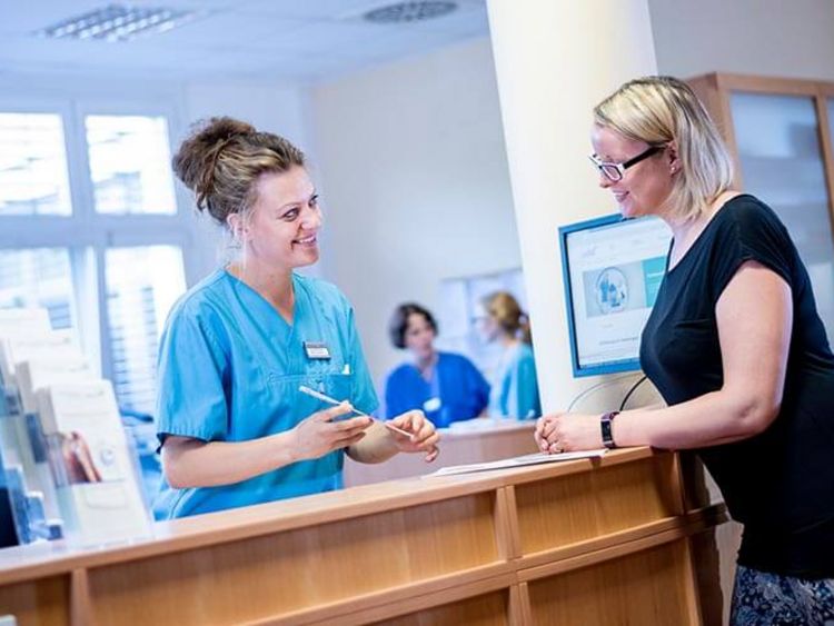 Patientin meldet sich an der Rezeption im Krankenhaus an