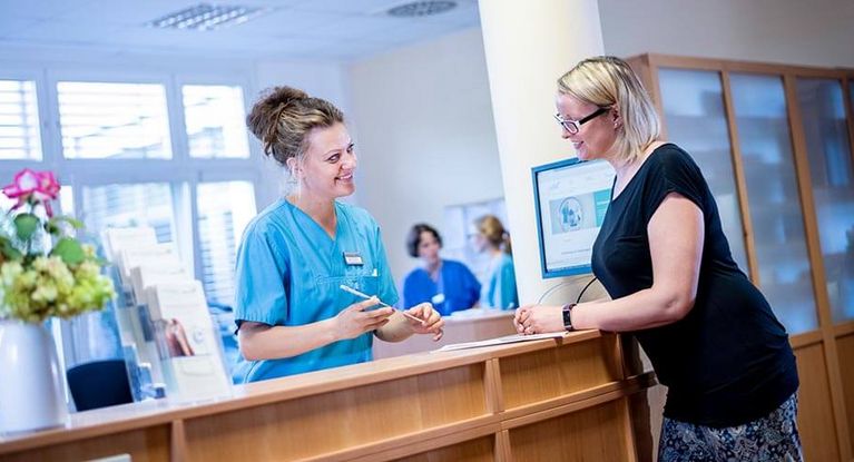 Patientin meldet sich an der Rezeption im Krankenhaus an