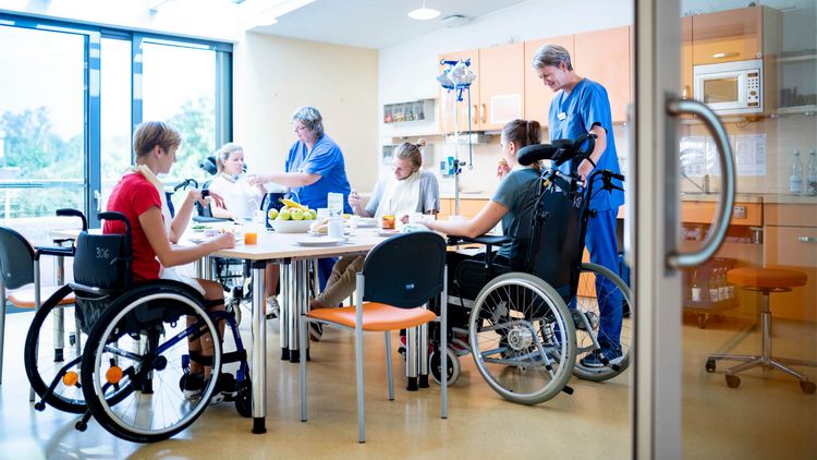 Patienten im Rollstuhl essen gemeinsam in der Therapieküche