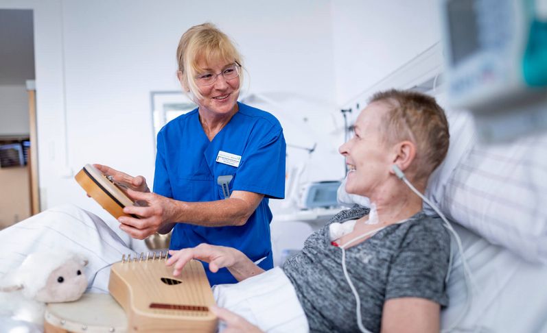 Pflegekraft und neurologische Patientin spielen auf kleinen Handtrommeln