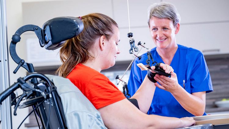 Therapeutin hilft Patientin im Rollstuhl beim Essen