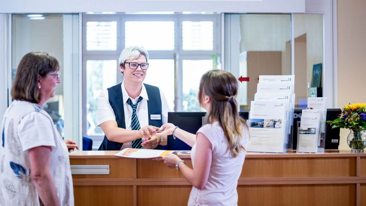 Patienten checken an der Rezption in der Klinik ein