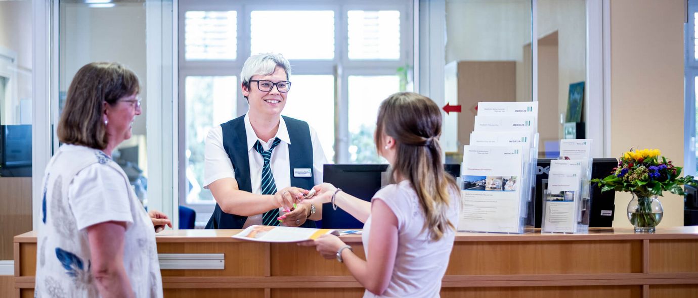 Patienten checken an der Rezption in der Klinik ein