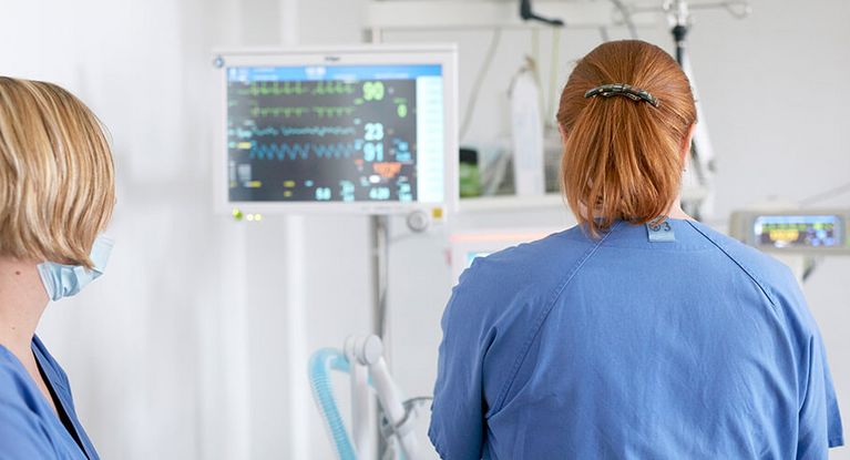 Pflegekräfte prüfen Vitalwerte am Bildchirm