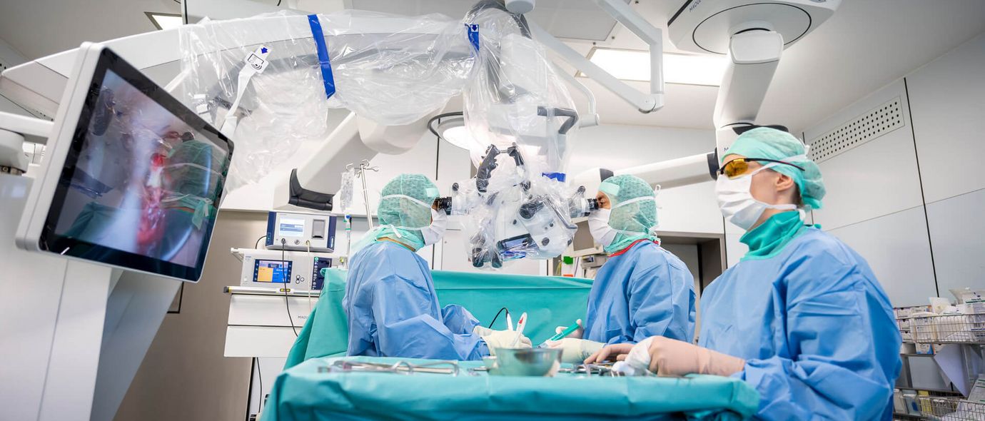 Arzt mit Mundschutz und Haube operiert Patienten