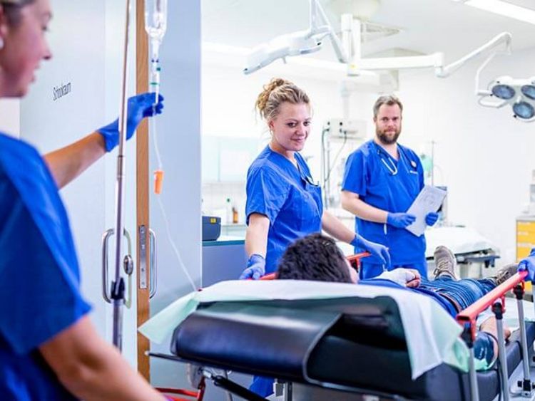 Pflegekräfte rollen Patienten auf der Krankentrage in den Operatonssaal