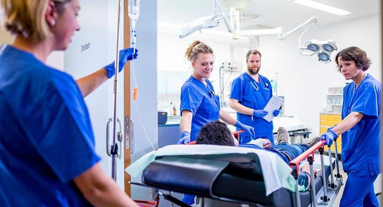 Pflegekräfte rollen Patienten auf der Krankentrage in den Operatonssaal