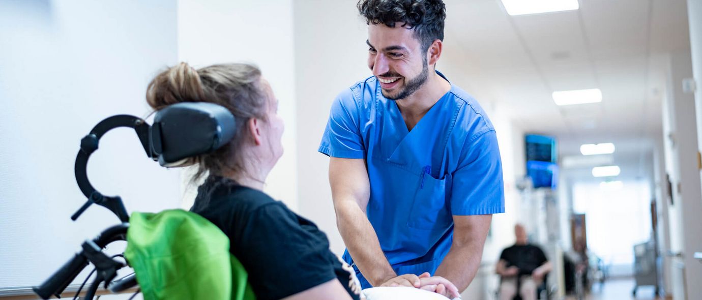 Pflegekraft spricht mit Patientin im Rollstuhl